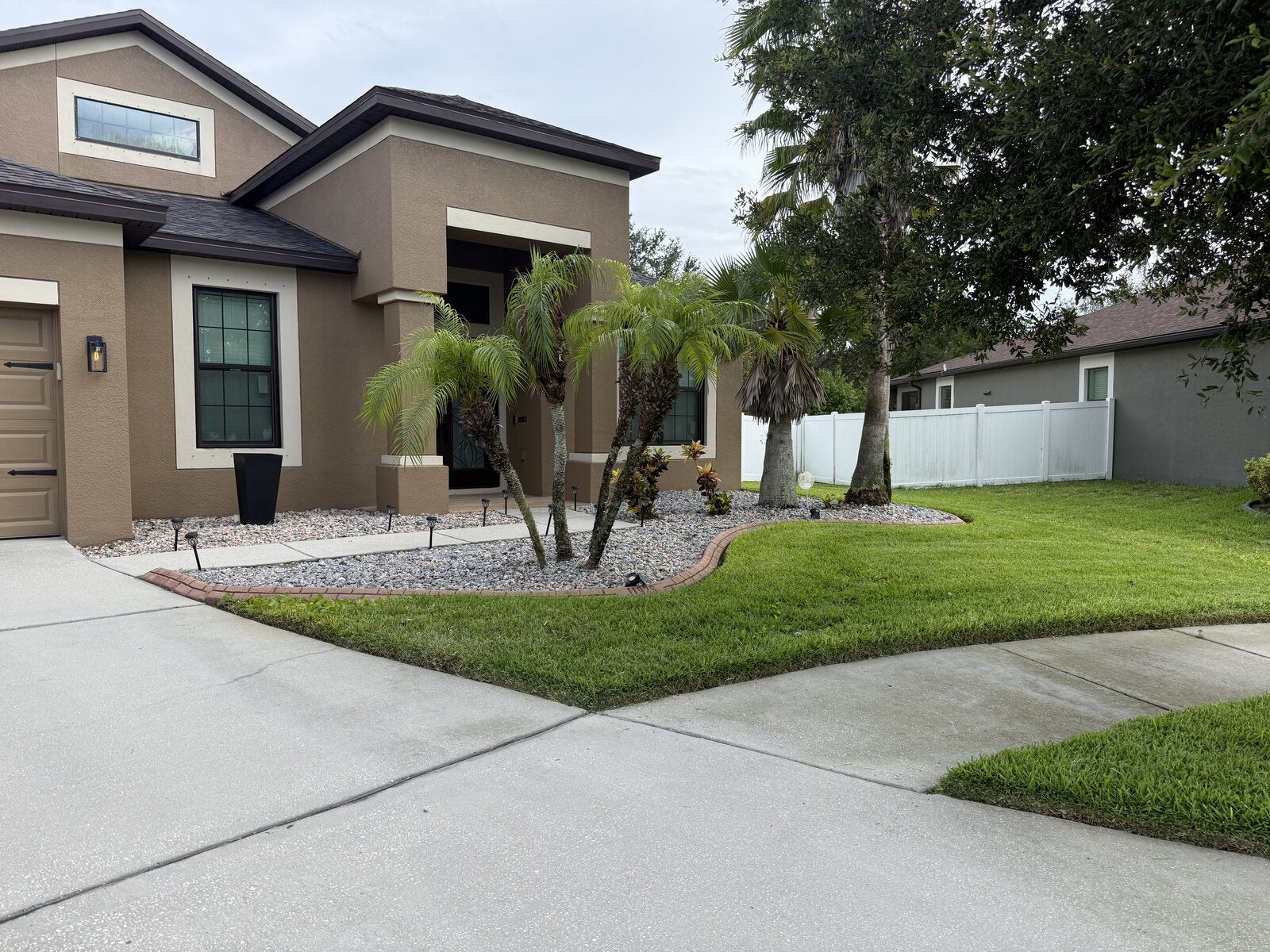 Manicured front yard with palms and stone landscaping by TruEdge